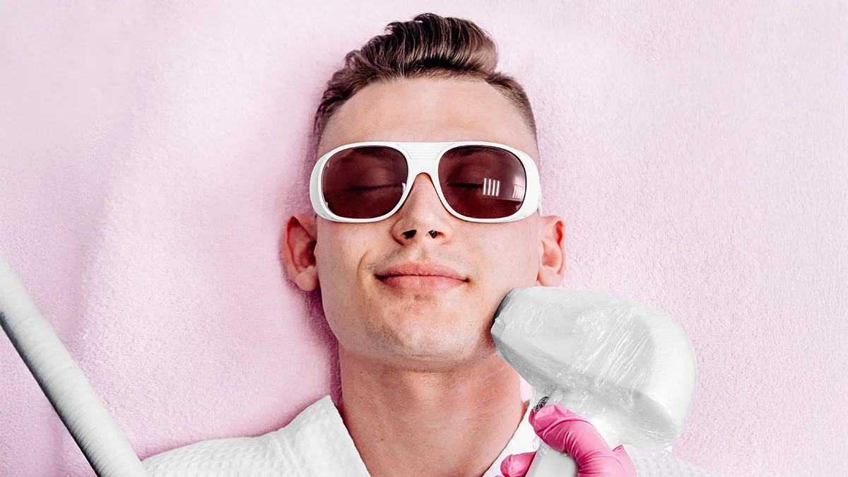 A cool young man in white sunglasses getting laser hair removal on face